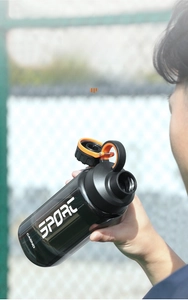 Detail of a charcoal gray sports bottle with dual-port lid and orange safety lock