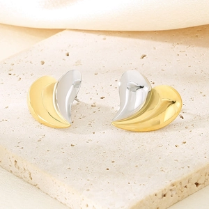 Détail macro de boucles d'oreilles cœur en fini or et argent sur un support en pierre