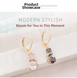 Close-up of cat pendant earrings with black and white zircon stones in gold plating
