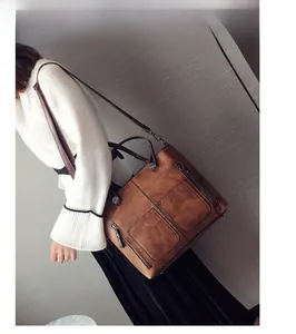 Close-up of vintage brown tote bag featuring dual front zipper pockets and matte texture