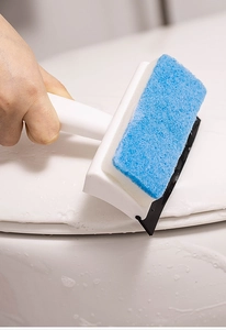 Close-up of dual-purpose cleaning brush scrubbing soapy white ceramic surface with sponge