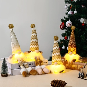 Golden knitted Christmas gnomes with LED lights on books and festive tree background