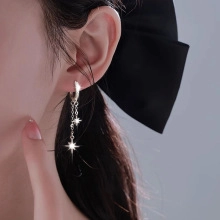 Silver star tassel earrings on a model with a black bow background and metal texture