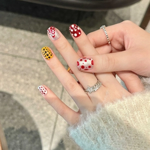Faux ongles artistiques à pois rouges et jaunes sur des pointes courtes et rondes