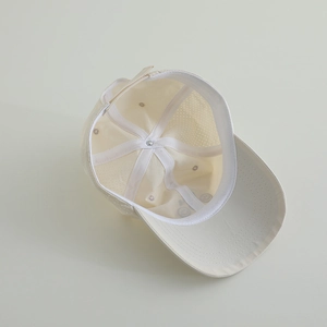 Detailed interior of a beige kids baseball cap showing mesh vents and smiley pattern
