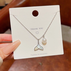 Detailed view of silver fishtail pendant with white mother of pearl and a round pearl