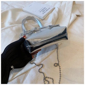 Close-up of silver pleated faux leather bag featuring double bows and metal chain strap