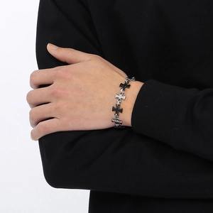 Detail shot of a minimalist black and silver cross-linked bracelet on a male wrist