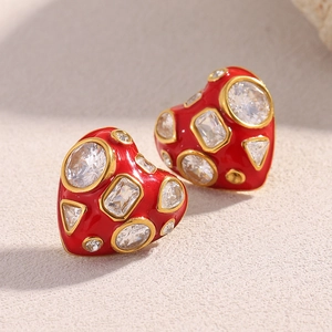 Detail of heart-shaped gold-plated earrings with red enamel and clear crystals