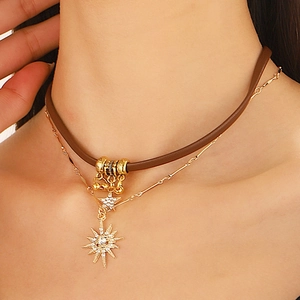 Detailed view of a double-layered brown leather choker with gold starburst pendant