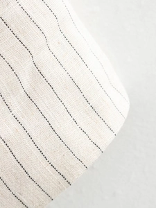 Detailed close-up of vertical black stripes on high-quality off-white linen fabric texture