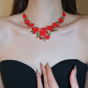 Close-up of red rose floral necklace with white pearls and gold leaves on a model