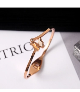Macro detail of rose gold butterfly cuff bangle featuring frosted wings and small zircon stone
