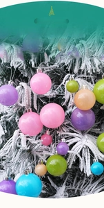 Boules de Noël macaron colorées avec finition brillante suspendues sur un sapin enneigé