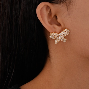 Macro shot of a butterfly stud earring with white zircons on a model's earlobe