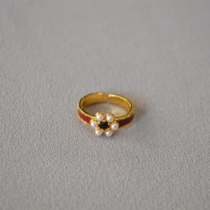 Macro detail of a vintage brass gold-plated flower ring with enamel and pearls