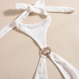 Detail of white ribbed halter dress featuring a gold shell-shaped metal buckle connector