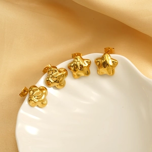Boucles d'oreilles étoiles en acier inoxydable doré 18 carats sur un plateau coquille