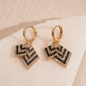Macro shot of gold hoop earrings with black and white crystal pave diamond shapes