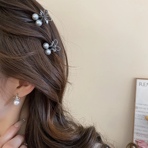 Detail view of mini bow pearl hair clips and matching earrings set on a model