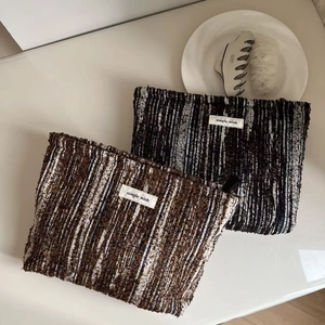 Close-up of textured tweed makeup bags with zipper and simple wish label