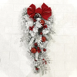 Detail of Christmas teardrop swag with red bow, flocking needles, berries and pine cones
