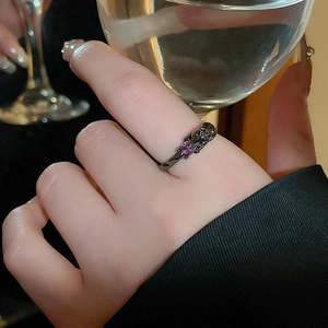 Close-up of vintage gothic ring with square purple gemstone on hand holding a glass