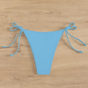 Detail of light blue bikini bottom with side ties on a rustic wooden background