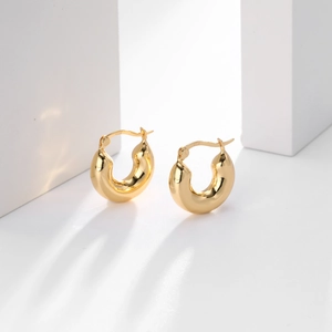 Close-up of gold-plated S925 sterling silver hoop earrings on white geometric blocks