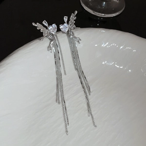 Vue macro d'ailes d'ange en cristal argenté et de longs glands de chaîne sur plat céramique