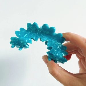 Detail of blue wavy claw clip with marble texture and strong grip teeth held by hand