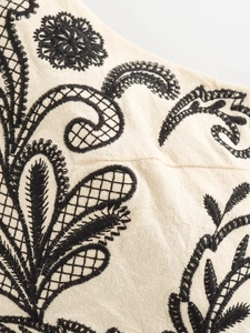 Macro detail of black floral embroidery on off-white cotton fabric for summer two-piece set