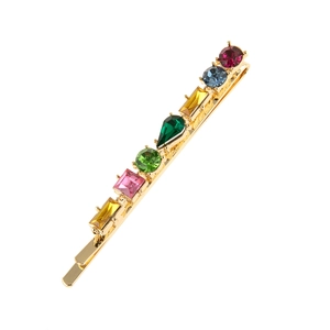 Détail d'une pince à cheveux dorée ornée de strass colorés de formes géométriques