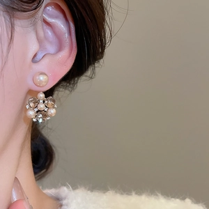 Dettaglio di orecchini a fiore con perle bianche e perline di cristallo su una modella
