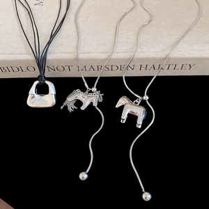 Detailed display of silver horse pendant necklace with brushed metal finish on books
