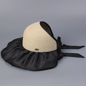 Détail d'un chapeau de soleil en paille avec bord en satin noir et nœud décoratif