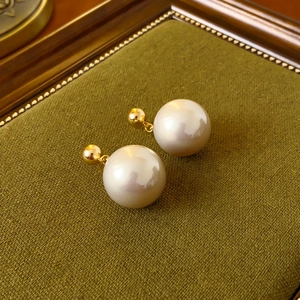 Macro view of gold-plated spherical stud earrings with lustrous round white pearls