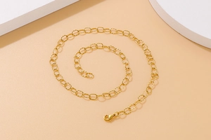 Macro shot of coiled golden metal cable chain necklace on minimalist geometric props