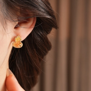 Gros plan de boucles d'oreilles gourde plaquées or 18K avec ambre et cristaux brillants