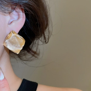 Gros plan de boucles d'oreilles carrées plaquées or avec texture martelée vintage