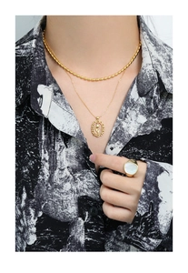 Detail of gold double-layer necklace with oval rose pendant and matching shell ring