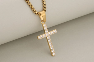 Detail of a gold cross pendant set with clear zircons on a delicate box chain