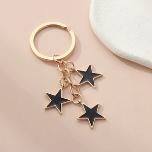 Detail of gold keychain with three tiered black enamel stars on light pink background