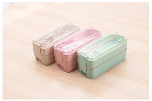Top view of 750ml wheat straw lunch boxes in beige, pink, and green on wood desk