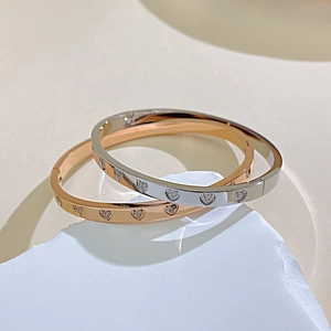 Detailed close-up of rose gold and silver heart-shaped stone-set stainless steel bangles