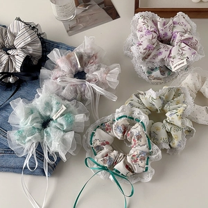 Detailed flat lay of lace floral scrunchies with bows and pearls on a stylish background