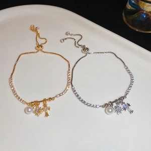 Detail of adjustable zircon cross bracelets in gold and silver with pearl accents