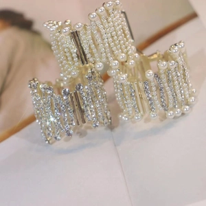 Detailed view of layered white pearls and silver rhinestone hair claws for high ponytails