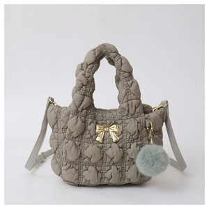 Detailed shot of grey quilted down cotton handbag with golden bow and plush charm