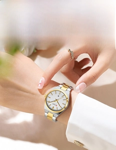 Close-up of a two-tone steel ladies watch on wrist with a date window and floral decor